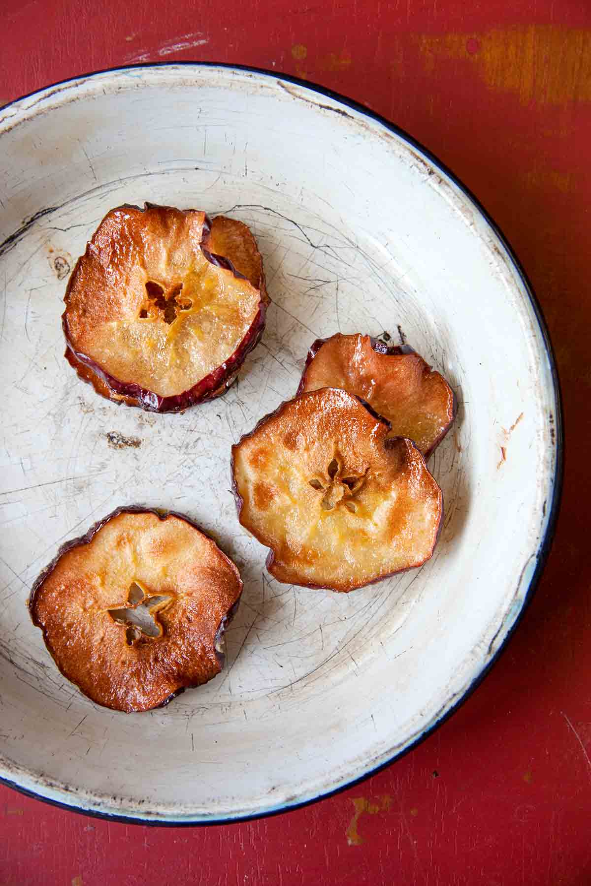 Four apple chips in a white pie dish.