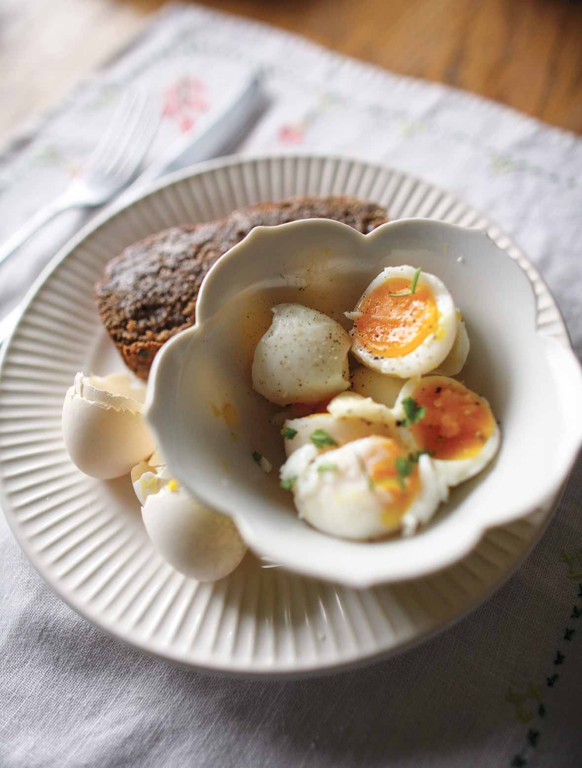 Halved soft-boiled eggs and toast on a plate with egg shells.