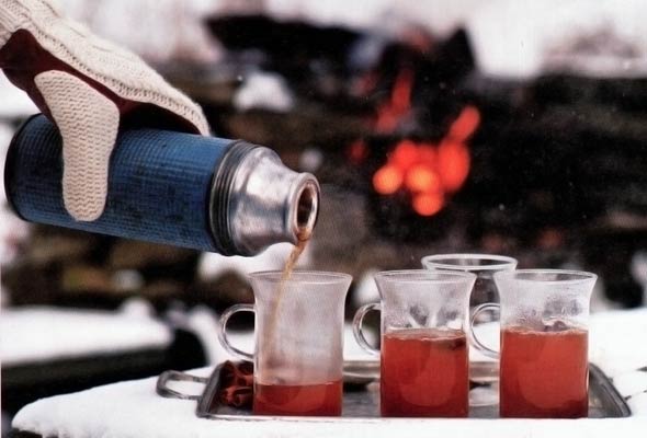 Apple spice bourbon hot toddies being poured into glasses from a thermos.
