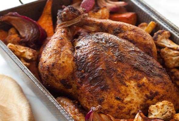 A deep roasting pan filled with roast chicken and vegetables