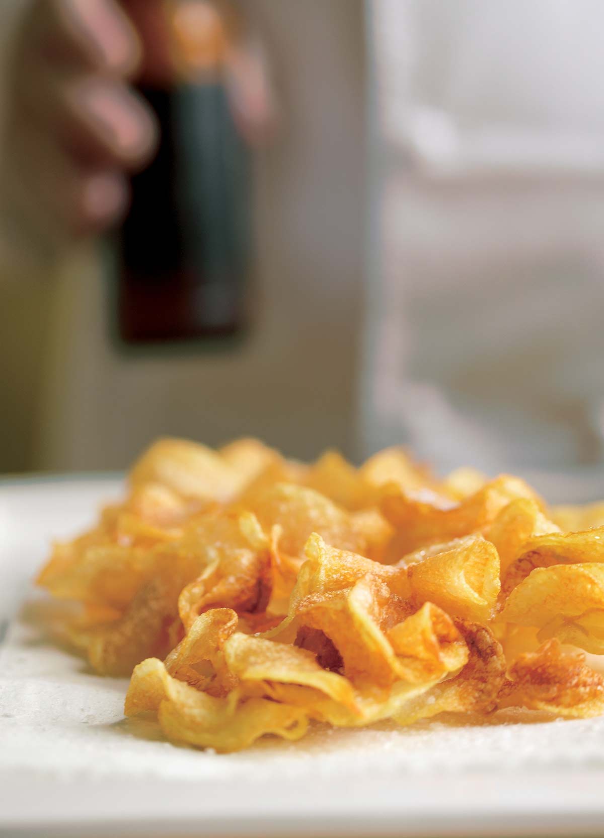 A pile of homemade potato ruffles on a white surface.