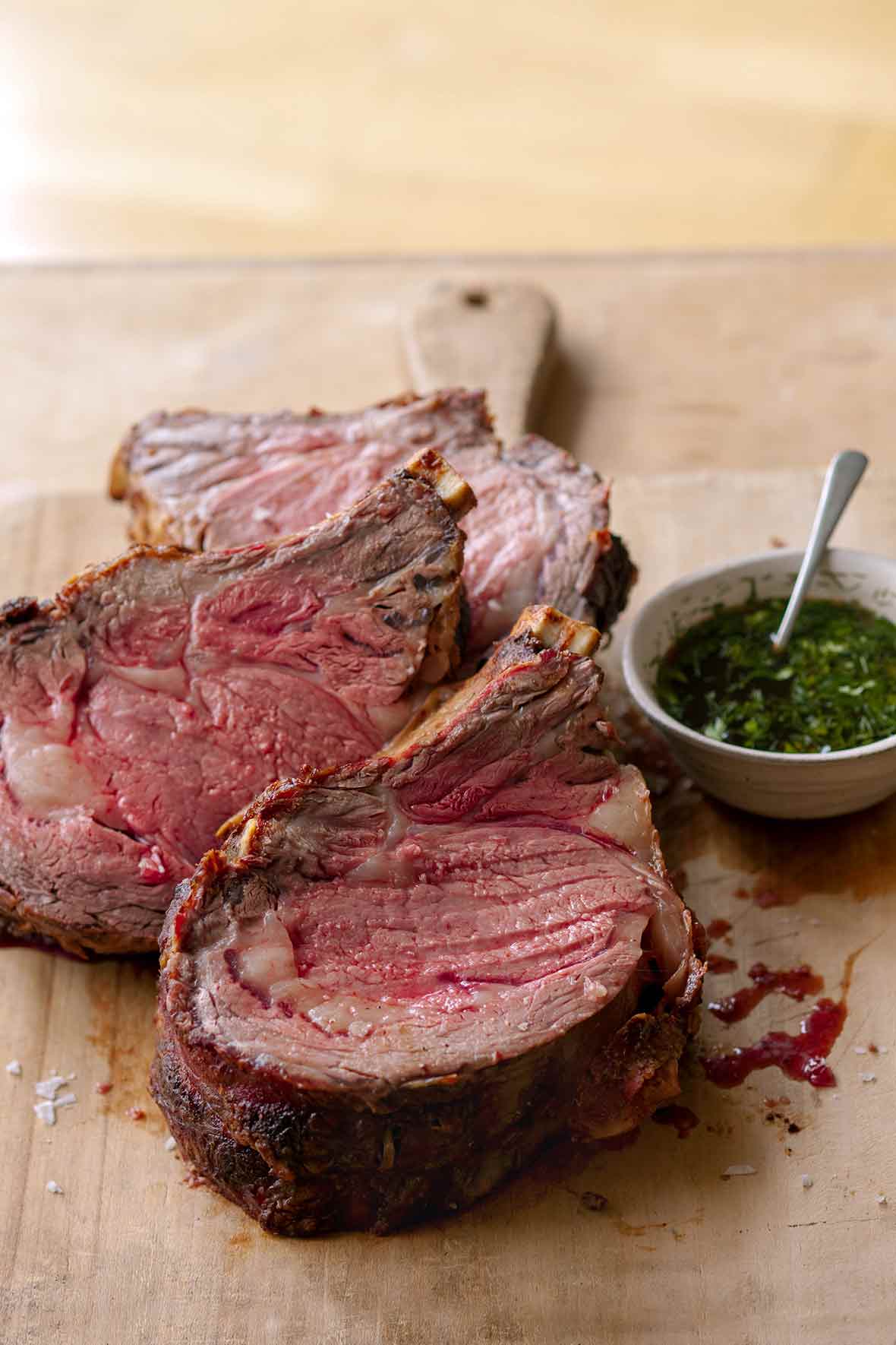 Three slice of medium rare standing rib roast au jus on a cutting board