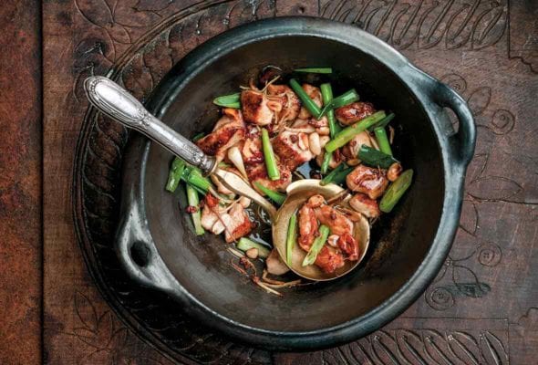 Black pottery bowl filled with the Chinese dish gung bao chicken
