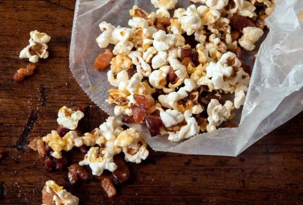 Open waxed paper bag with popcorn and maple bacon bits spilling out