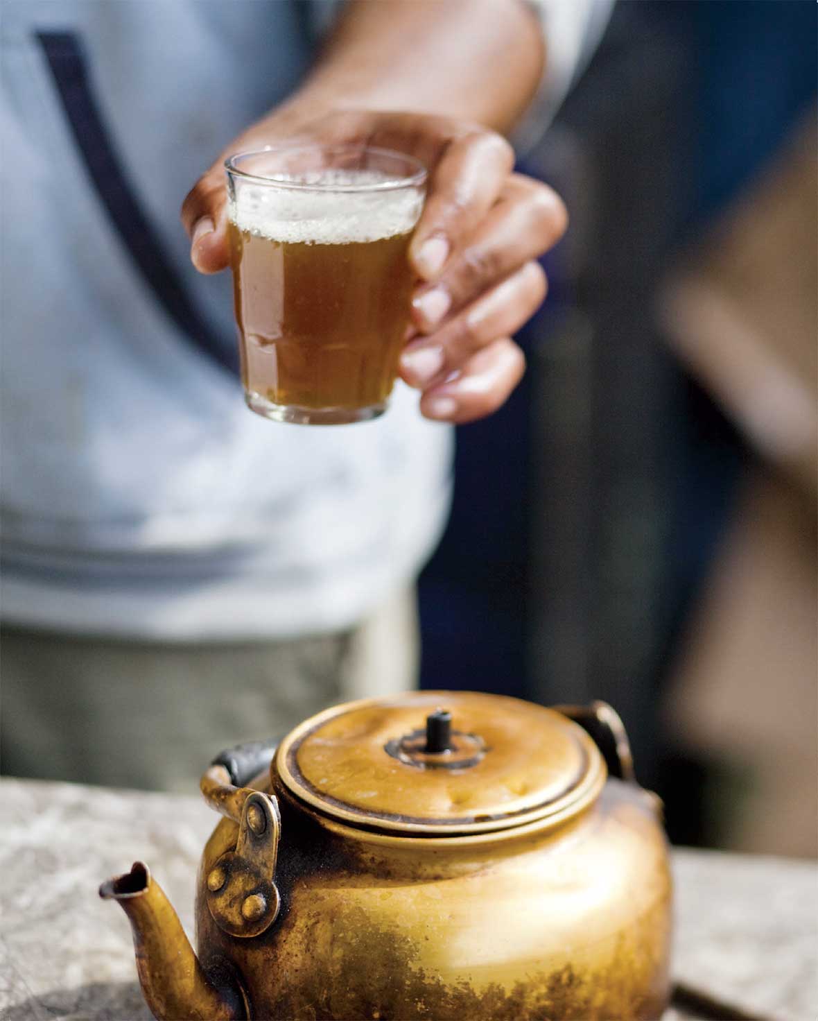 A tumbler filled with amber liquid and a teapot in the foreground