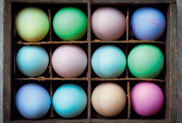 A crate filled with an assortment of dyed easter eggs.