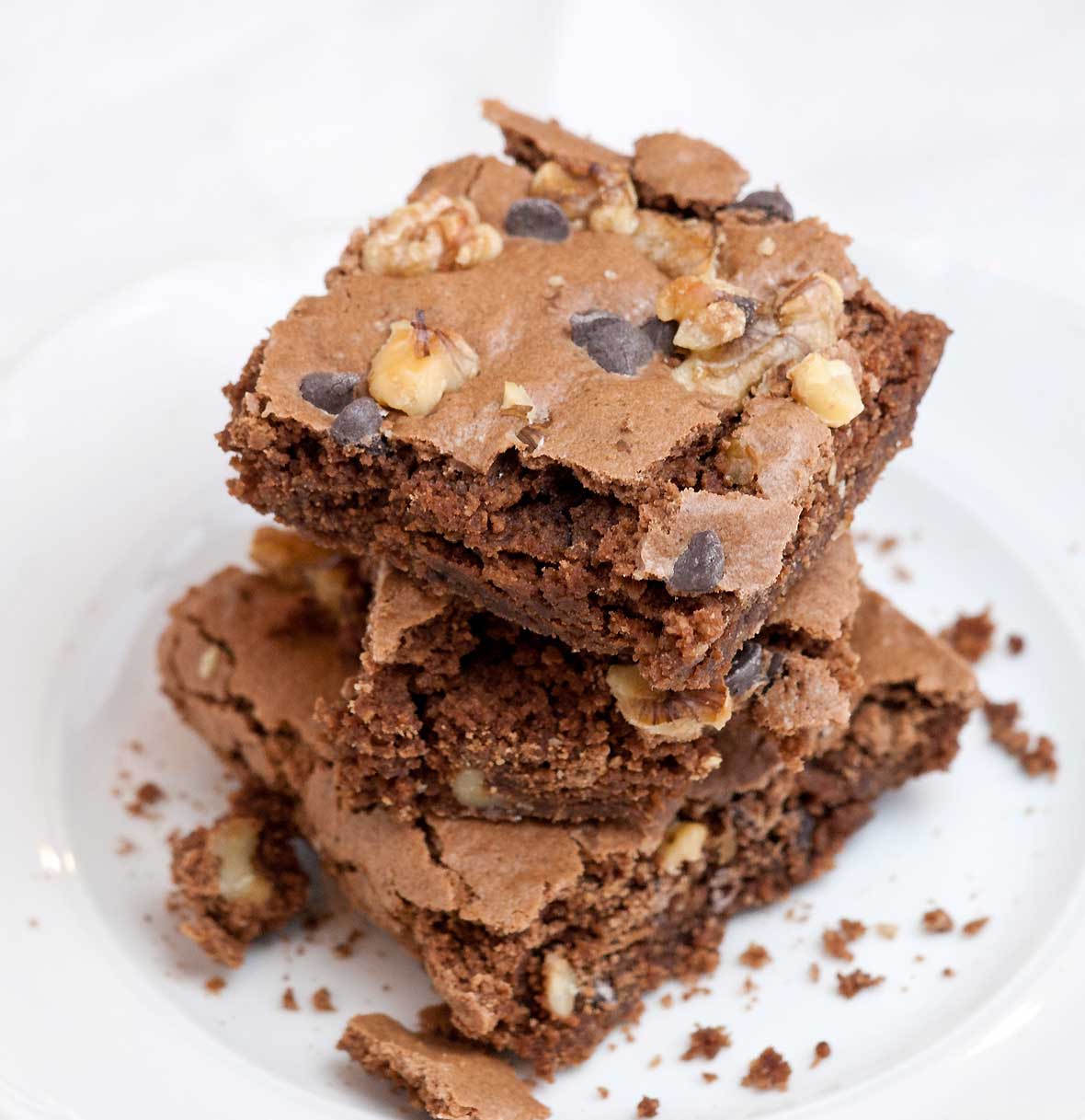 Three Passover brownies stacked on top of each other on a white plate.