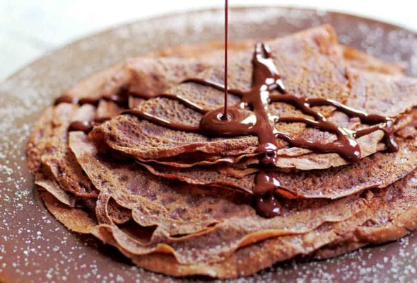 A stack of Tom Aikens' chocolate crepes being drizzled with chocolate sauce.