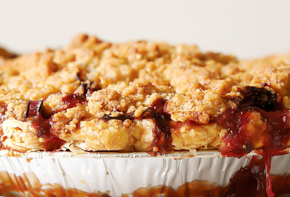 A side view of a strawberry rhubarb pie with ginger crumb topping.