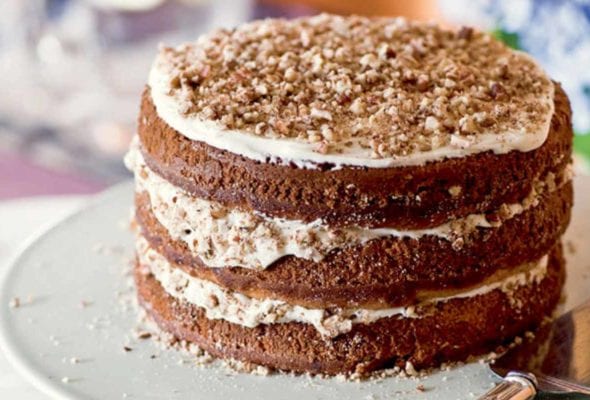 A three-layer hummingbird cake with a cake server beside it.
