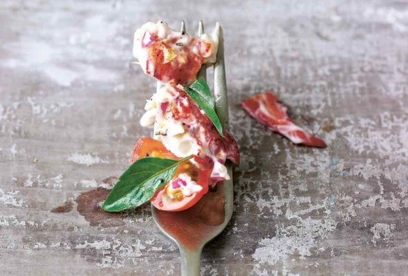 Fork with lobster salad and tomato salad, two small leaves of basil