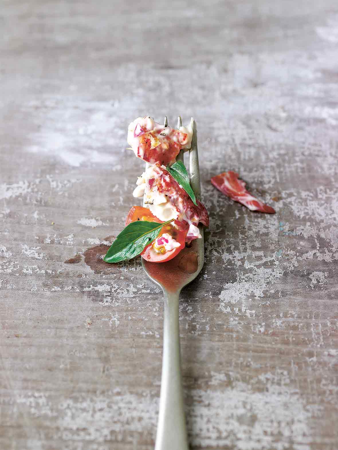 Fork with lobster salad and tomato salad, two small leaves of basil