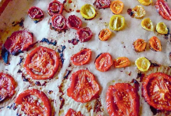 A rimmed baking sheet filled with assorted oven-roasted tomatoes.