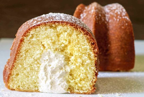 A slice of twinkie bundt cake dusted with confectioners' sugar and turned to show the cross section.