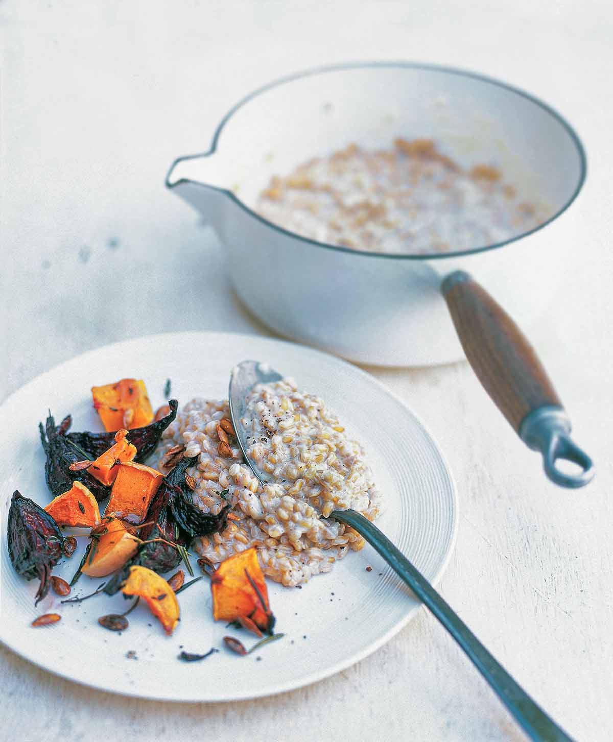 A plate of whole spelt risotto with butternut squash and beets, with an enamel pot of risotto beside it.