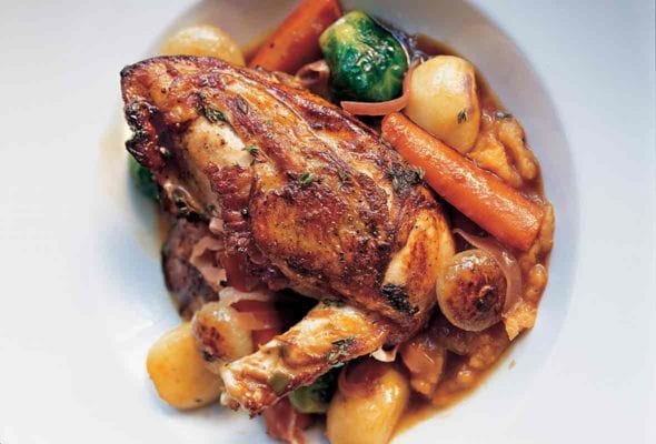 A large white serving bowl filled with chicken with autumn vegetables and Madeira wine.