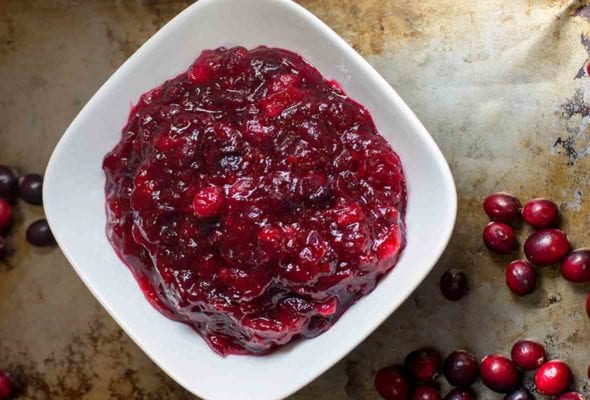 Cranberry and orange relish in a white bowl on a baking sheet