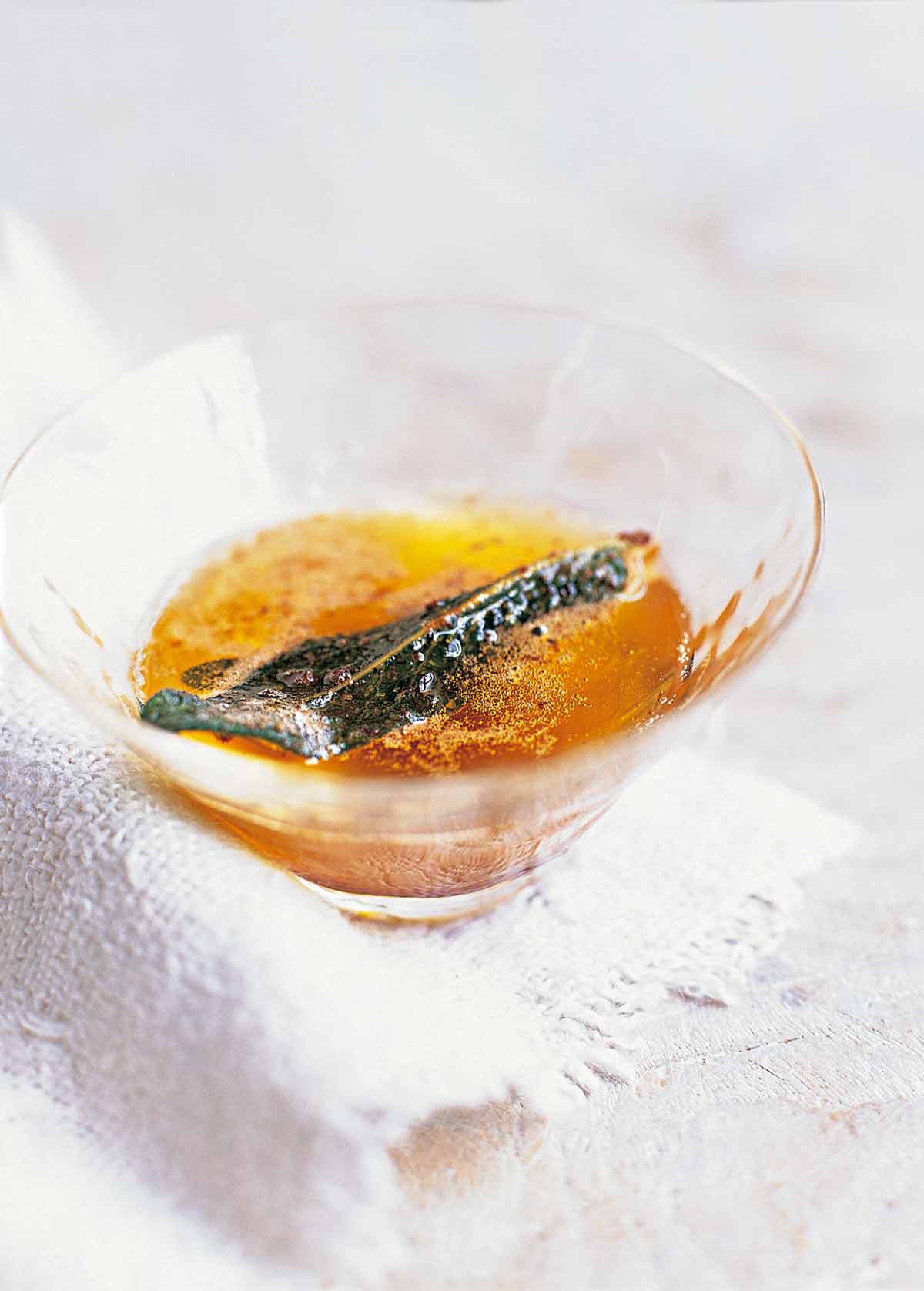 Sage brown butter with a crispy sage leaf in a small glass.
