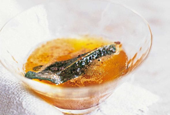 Sage brown butter with a crispy sage leaf in a small glass.