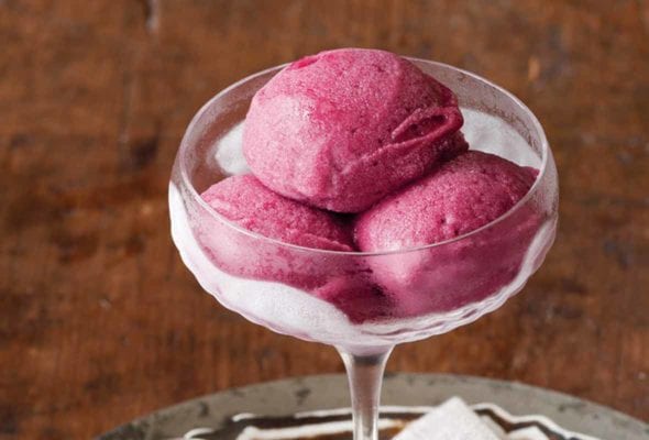A coupe class with three scoops of red mulled wine sorbet