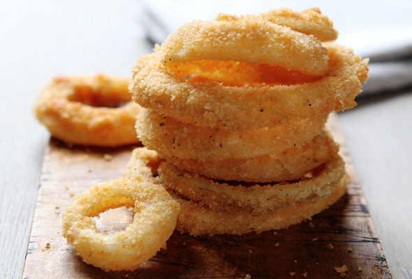 A stack of moonshine onion rings on a wooden board.