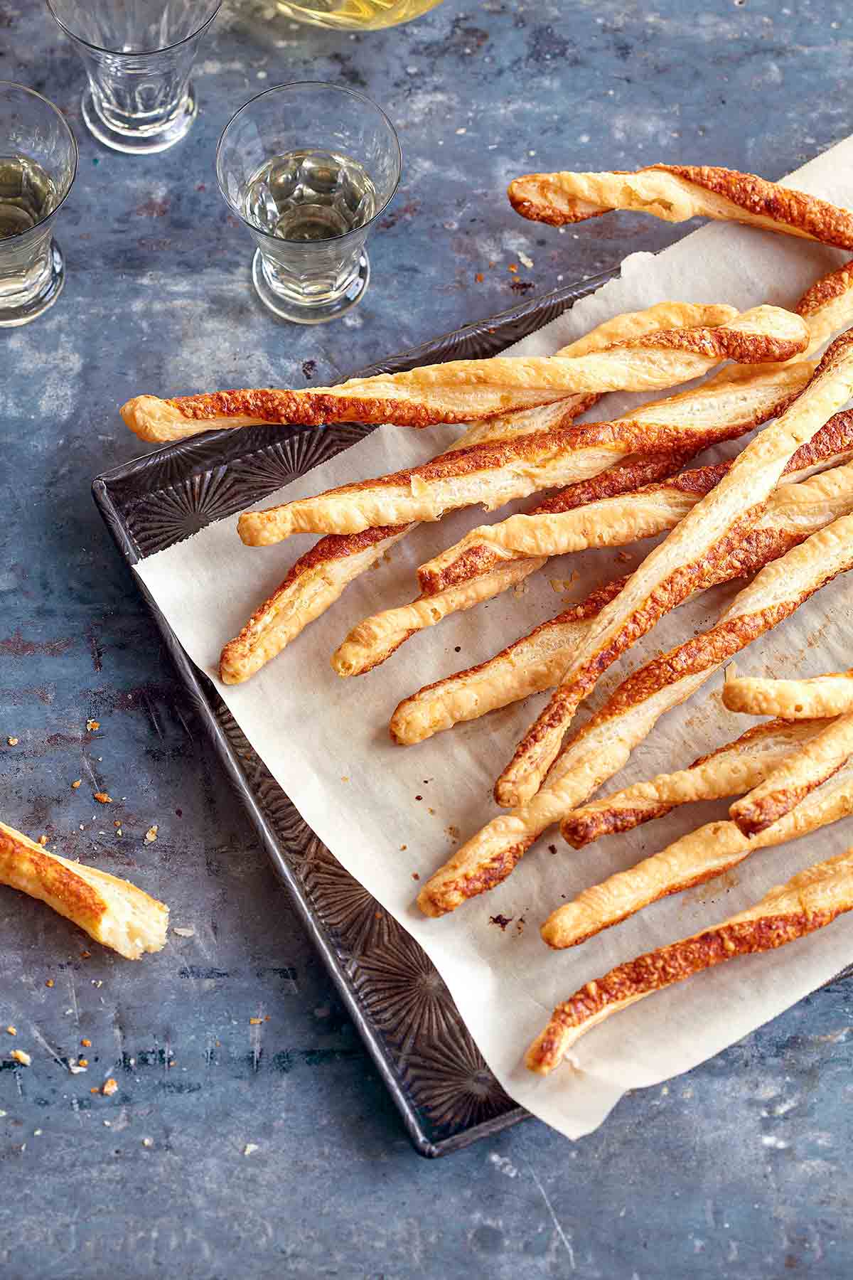 A layer of parmesan twists on a parchment-lined baking sheet.