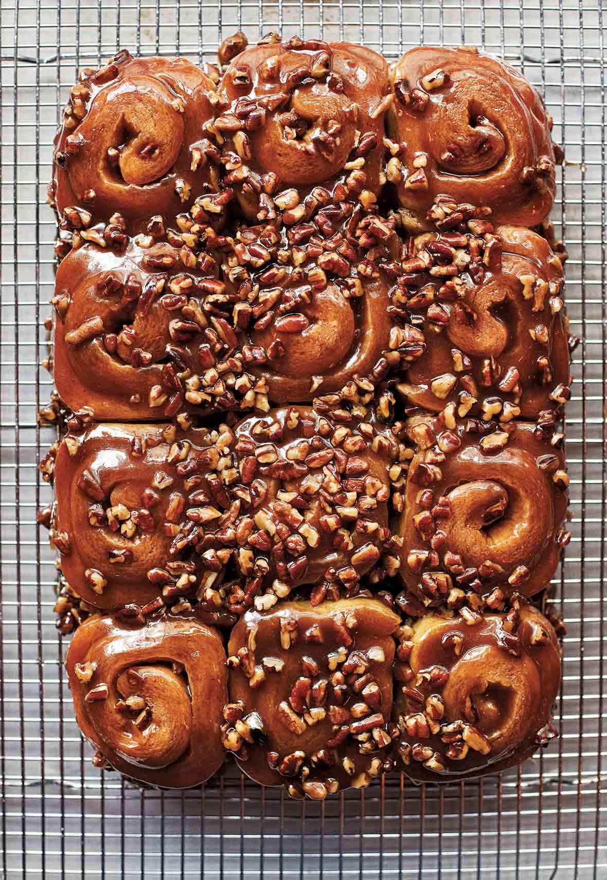 12 schnecken, pecan cinnamon buns, covered with pecan-caramel topping, and chopped pecans on a wire rack