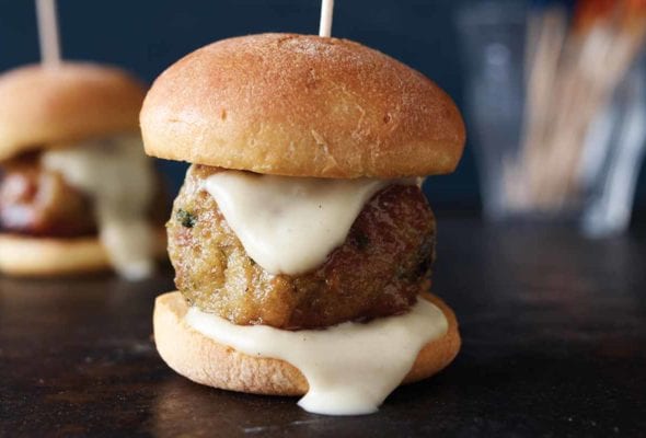 Two chicken meatball sliders with white sauce and toothpicks holding them together.