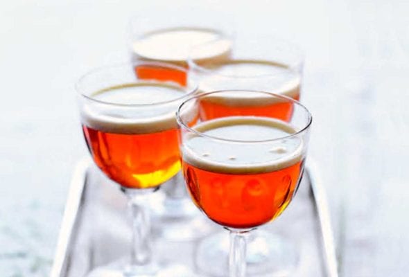 Four aperitif glasses filled with little hot after dinner shots on a silver tray.