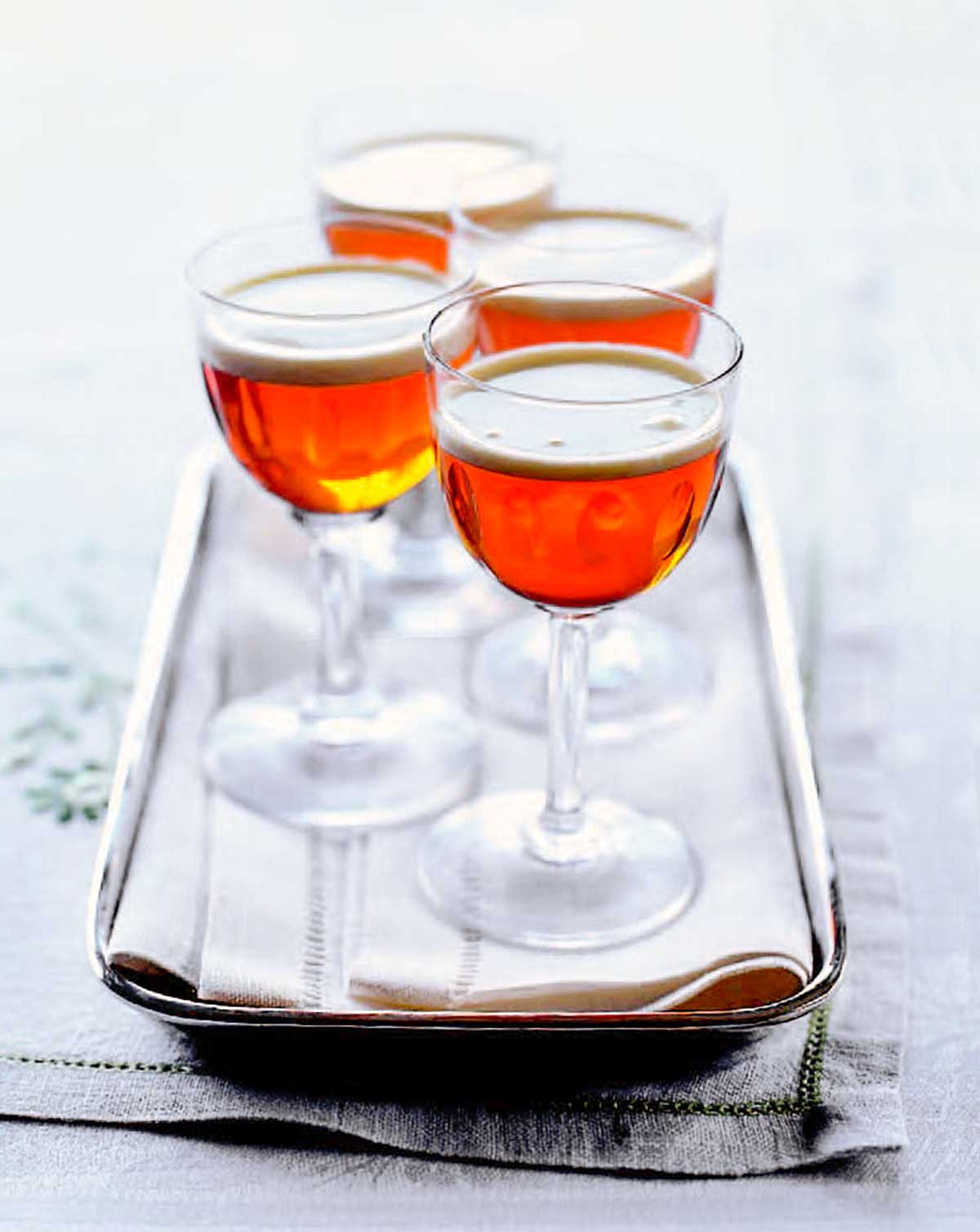 Four aperitif glasses filled with little hot after dinner shots on a silver tray.