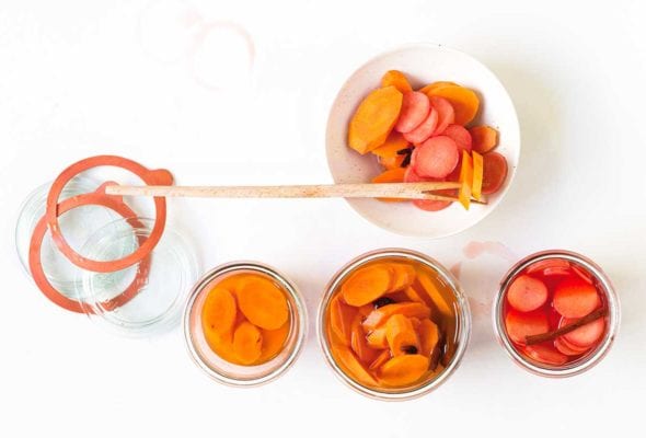 Three pickling jars with carrots and beets, a bowl on the side