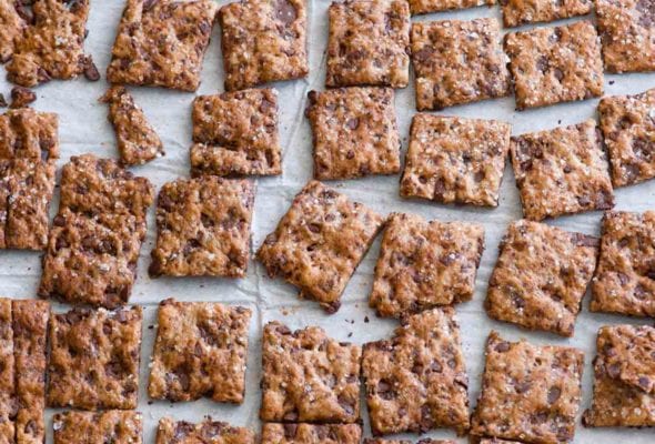 Squares of chocolate chip crisps on a sheet of parchment paper.