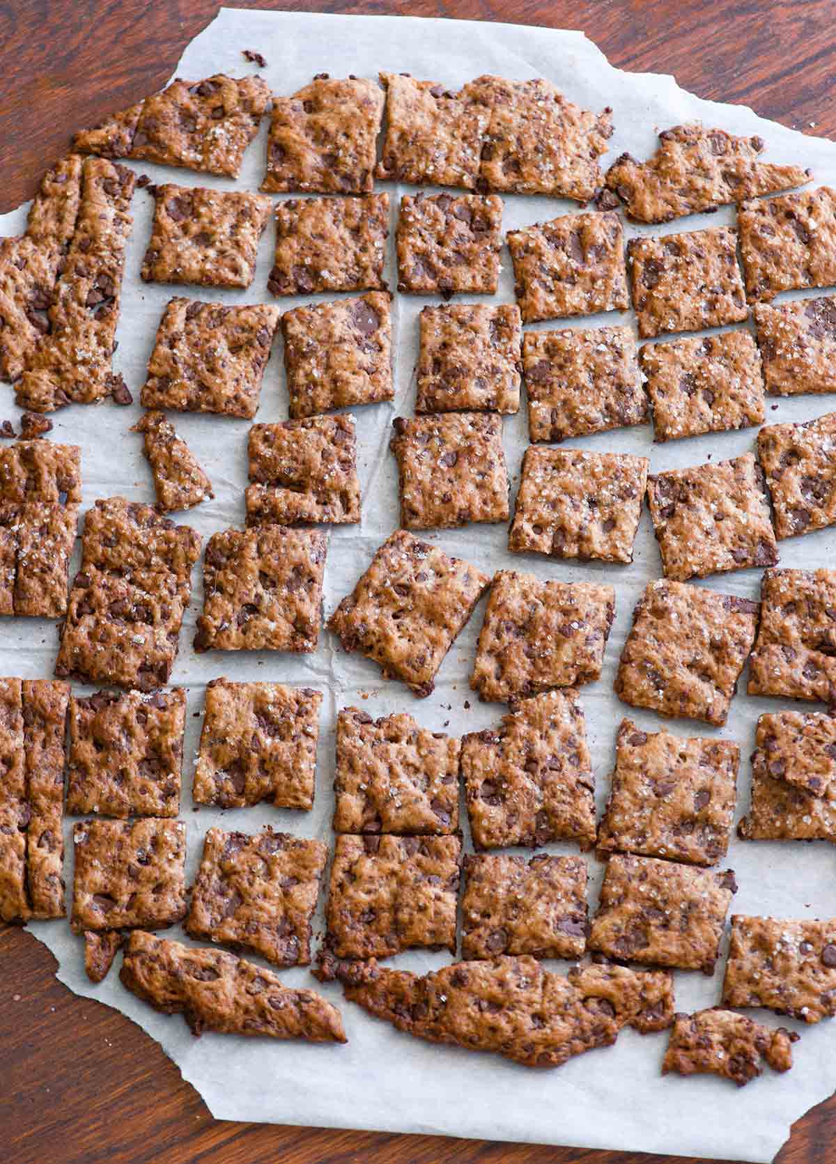 Squares of chocolate chip crisps on a sheet of parchment paper.