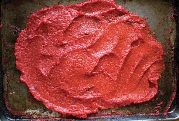 A rimmed baking sheet spread with a thick layer of homemade tomato paste.
