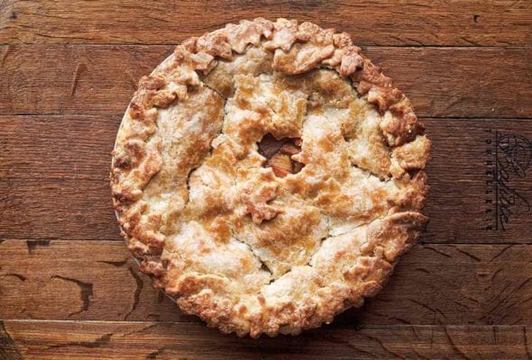 A baked hot buttered rum apple pie on a wooden board.