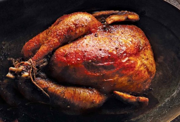 A whole roast chicken with Moroccan spices on an oval serving platter.