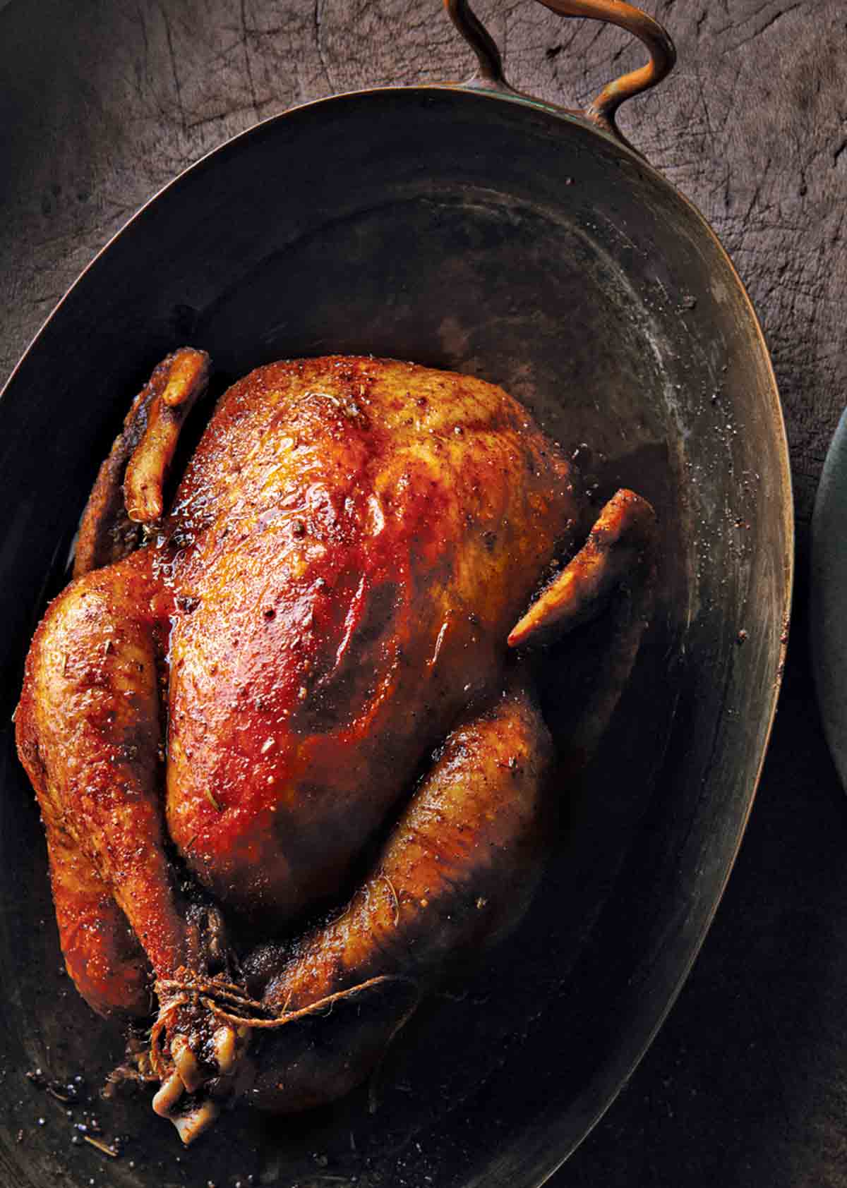 A whole roast chicken with Moroccan spices on an oval serving platter.