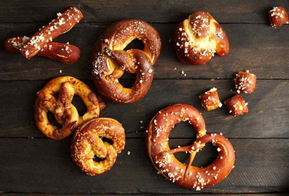 Soft pretzels of assorted shapes and sizes on a wooden surface.
