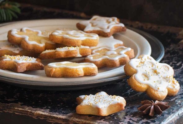 A white plate with a pile of sugar cookies coated in a champagne glaze.