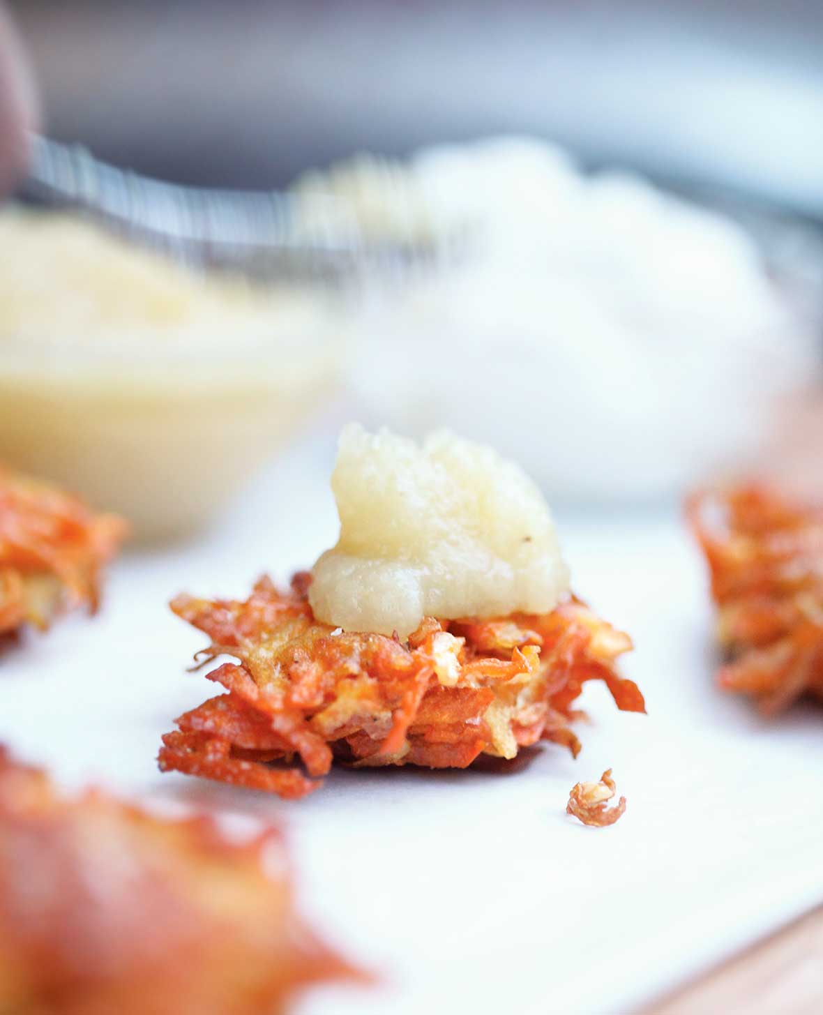 A root vegetable latke topped with a dollop of applesauce.
