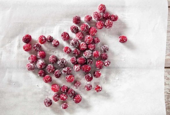 Several sugared cranberries scattered across a sheet of parchment.