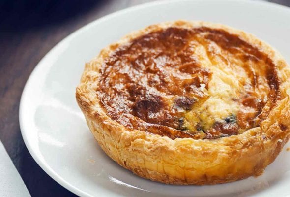 A baked mini quiche for one on a white plate.
