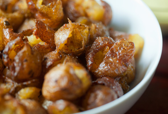 A white bowl filled with smoked pickled potatoes with anchovy aioli in a bowl on the side.