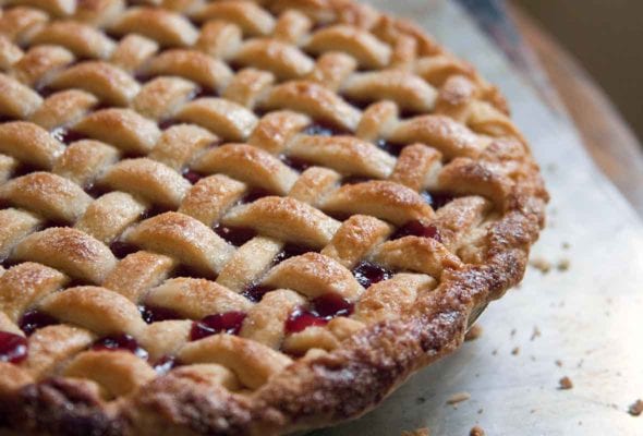 A lattice-topped cherry pie on a baking sheet.
