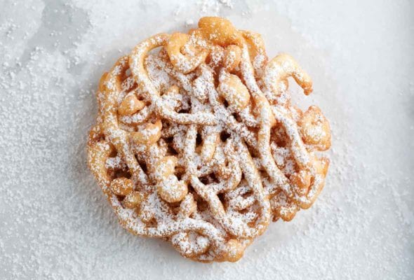 A mini funnel cake dusted with confectioners' sugar.