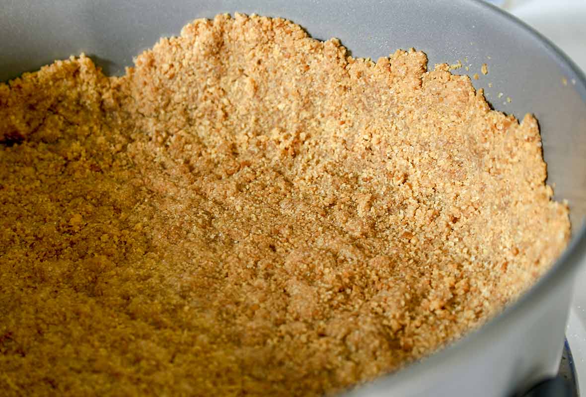 A baking pan with a graham cracker crust pressed into it