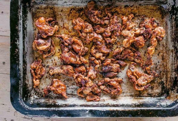 An old roasting pan filled with cooked nuggets of chicken skin