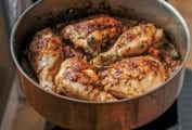 A skillet with browned chicken pieces cooked with mustard, wine, and thyme
