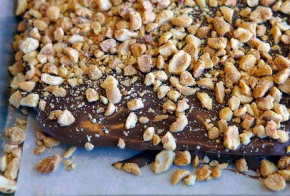 A slather of chocolate topped with chopped roasted peanuts on parchment