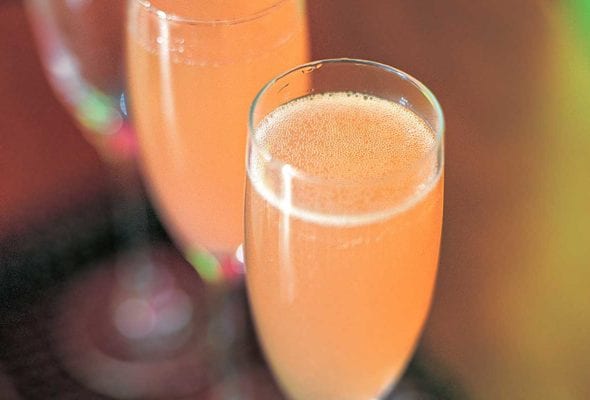 Two Champagne flutes filled with Campari fizz.